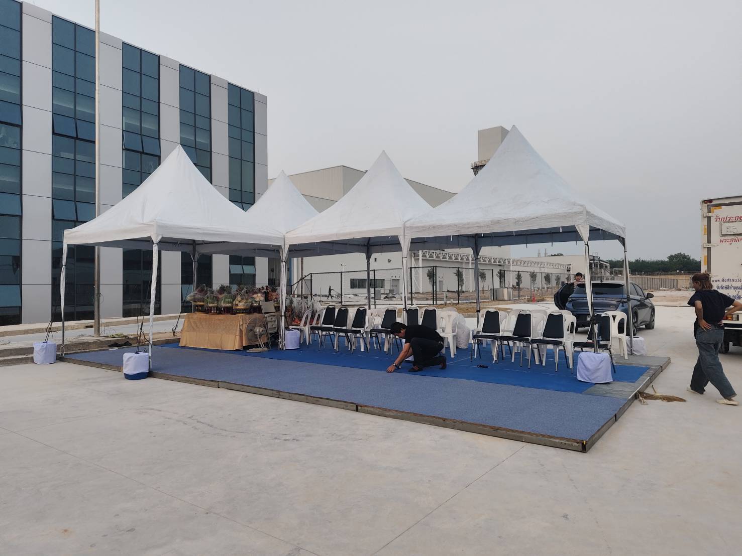เต็นท์ โต๊ะ และเก้าอี้ที่จัดเตรียมสำหรับงานพิธีในโรงงาน